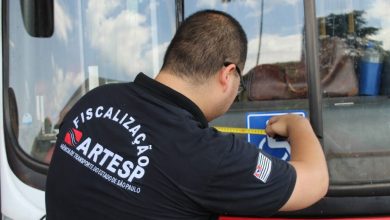 Fiscal da Artesp mede adesivo de acessibilidade em um ônibus durante inspeção. Concurso Artesp 2025 tem vagas para fiscalização de transporte.