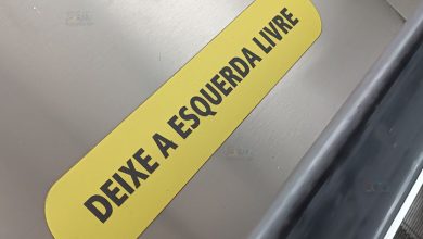 Adesivo amarelo com a inscrição 'Deixe a esquerda livre' colado ao lado de uma escada rolante.