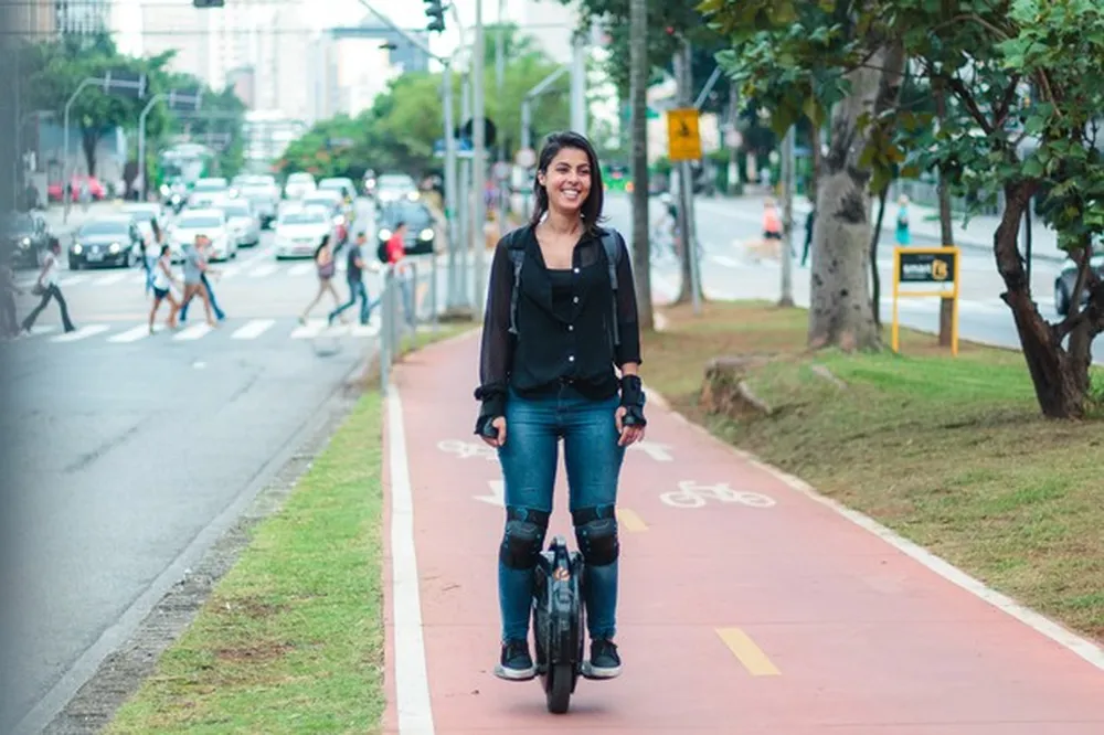 Mulher pilotando um monociclo elétrico em ciclovia urbana, destacando segurança e regulamentação para monociclos elétricos no trânsito.