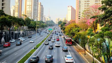 Avenida movimentada em São Paulo com carros e ônibus durante o dia, representando o custo de locomoção em São Paulo 2025.