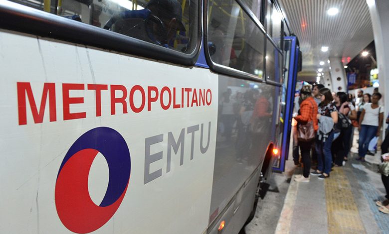 Ônibus da EMTU no terminal metropolitano com passageiros embarcando.