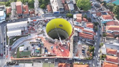 Poço de escavação da linha 6 do metrô de SP visto de cima, em área urbana com canteiro de obras ativo.