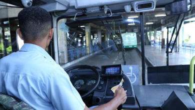 Motorista conduz ônibus urbano em terminal, ilustrando como se tornar motorista de ônibus no Brasil.