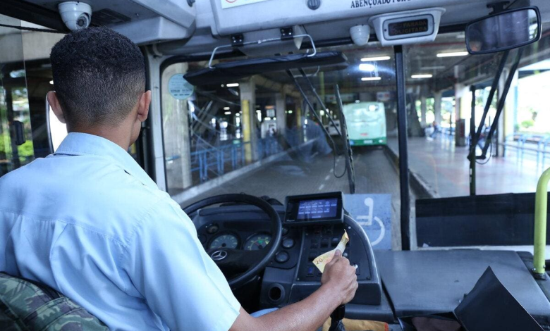 Motorista conduz ônibus urbano em terminal, ilustrando como se tornar motorista de ônibus no Brasil.
