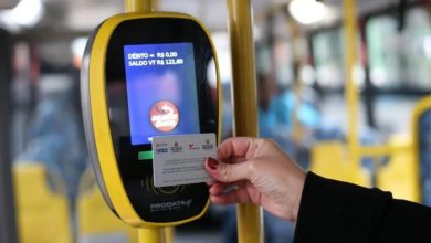 Pessoa usando o Bilhete Único em validador eletrônico dentro de um ônibus.