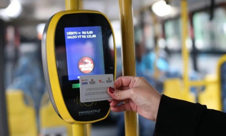 Pessoa usando o Bilhete Único em validador eletrônico dentro de um ônibus.