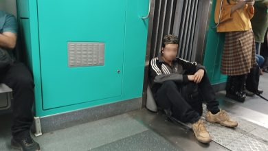 Passageiro sentado no chão do trem, o que é proibido, ocupando espaço e colocando em risco a segurança e higiene no transporte público.
