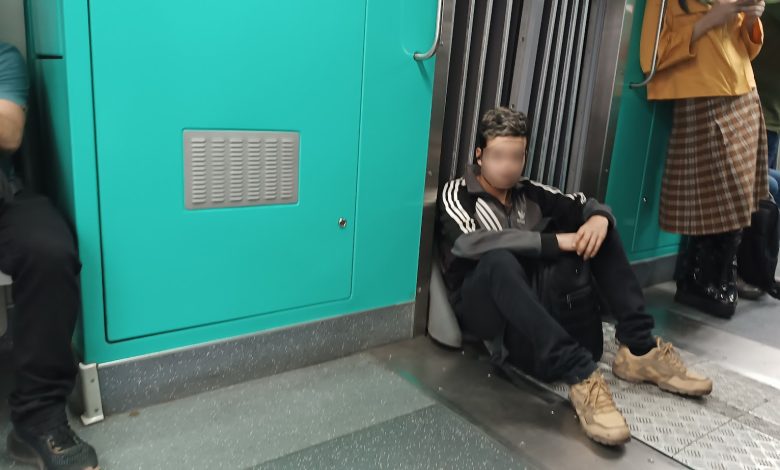 Passageiro sentado no chão do trem, o que é proibido, ocupando espaço e colocando em risco a segurança e higiene no transporte público.