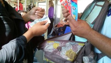 Vendedor ambulante no trem oferecendo produtos a passageiro, prática comum apesar da proibição do comércio ambulante nos trens.