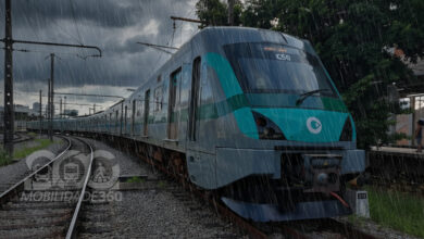 Trens da Linha 8-Diamante operando sob forte chuva em São Paulo, com o céu escuro ao fundo.