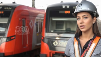 Mulher com capacete da CPTM e colete de segurança, com dois trens novos ao fundo, simboliza o futuro da CPTM.