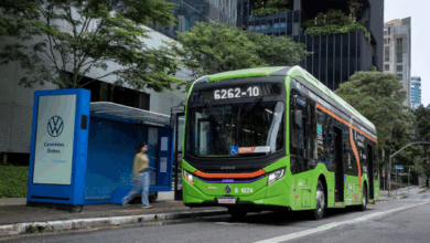 Ônibus elétrico verde de SP parado em ponto de ônibus na cidade.