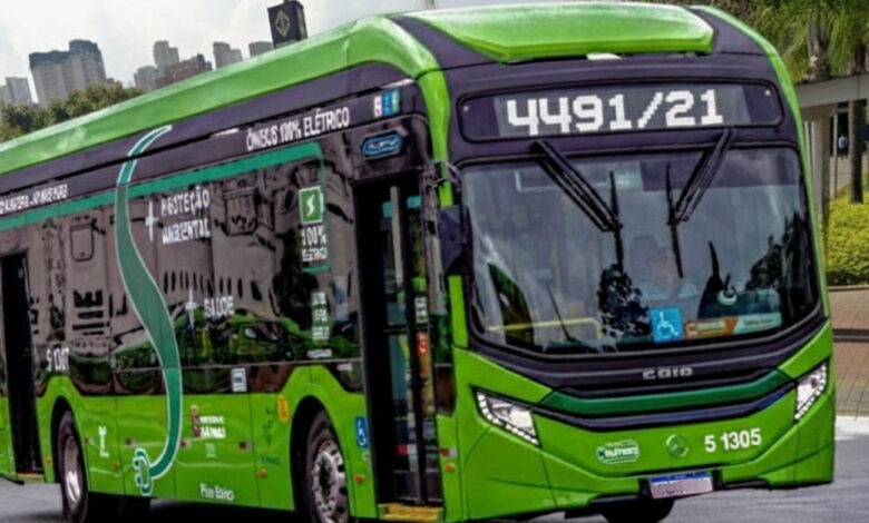 Ônibus verde da nova linha 4491/21 da SPTrans, elétrico, na rua, com prédios ao fundo.