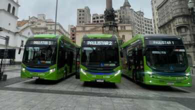Três ônibus verdes das linhas Paulistar estacionados em praça de São Paulo com prédios históricos ao fundo.