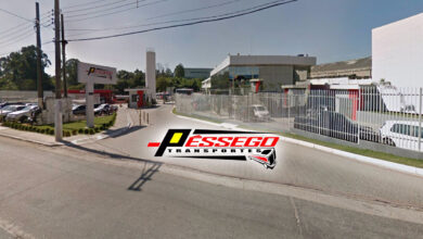 Imagem da sede da Pêssego Transportes com logo visível, mostrando a entrada e a frota de veículos da empresa.