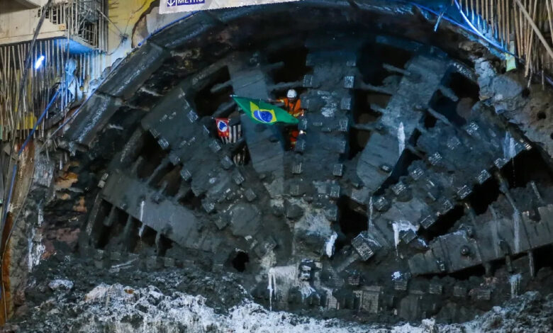 Operário com bandeira do Brasil na frente de tatuzão durante a escavação de túnel para a futura Linha 19-Celeste do Metrô.
