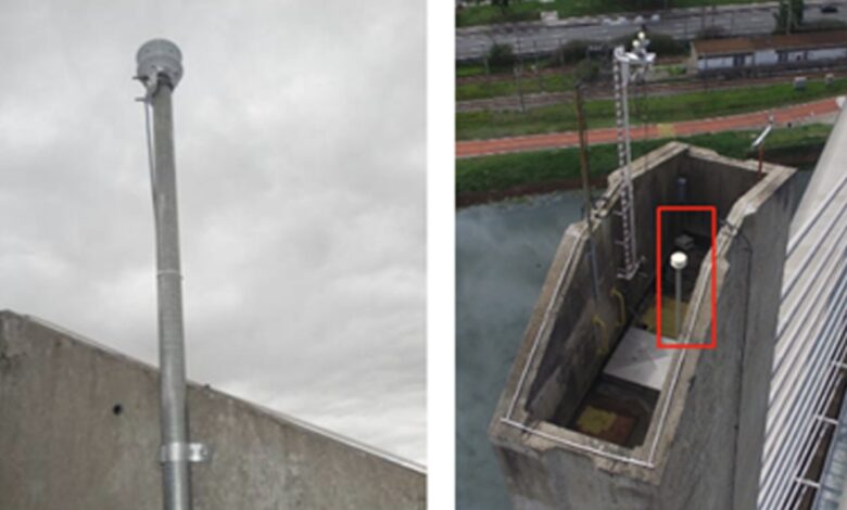 Foto mostrando uma torre de monitoramento climática, com um dispositivo de medição, em área próxima à ferrovia. Palavras-chave: