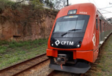 Trem da CPTM circulando na via férrea em meio à vegetação.
