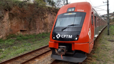 Trem da CPTM circulando na via férrea em meio à vegetação.