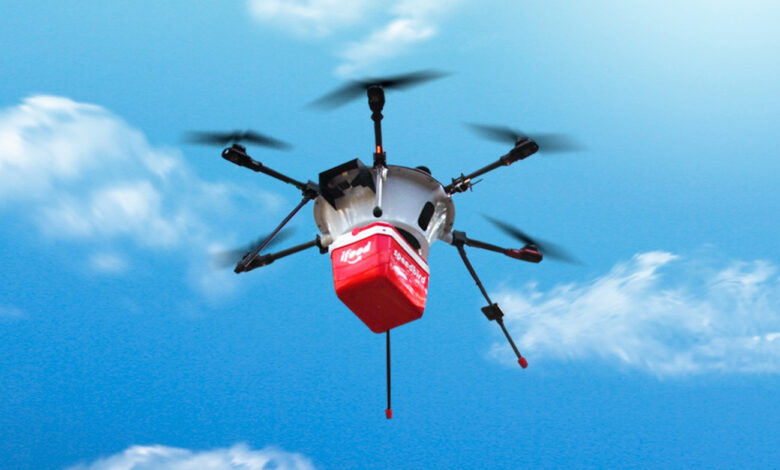 Drone do iFood com pacote vermelho voando sob céu azul com nuvens. Representa o futuro do delivery por drones iFood.
