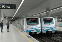 Renderização da Estação Dutra da Linha 2-Verde, com dois trens parados na plataforma. Passageiros aguardam.